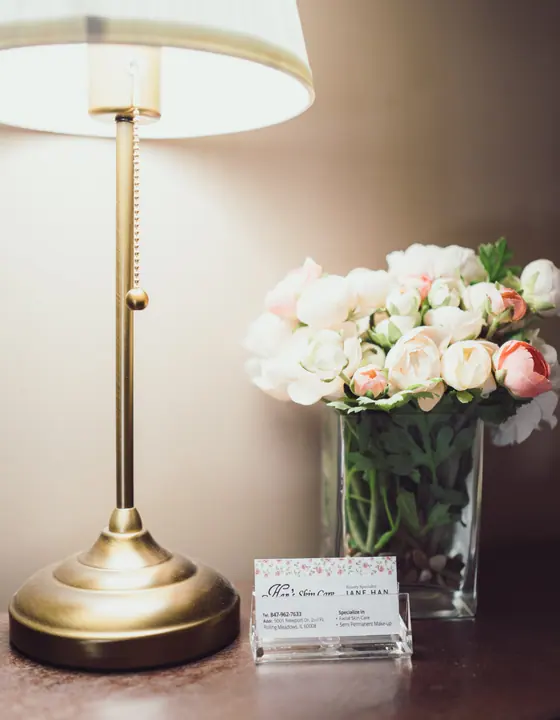 Flowers and Han's Skin Care business card beside a lamp